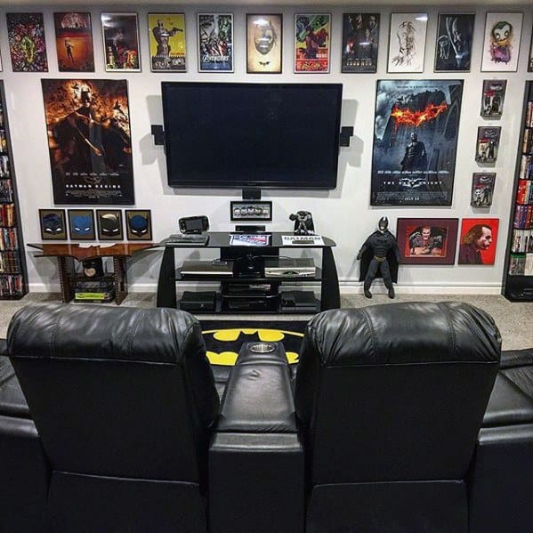 Home theater with leather seats, a large TV, superhero posters, and collectibles on the shelves and walls