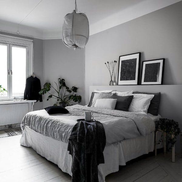 Scandinavian bedroom with gray walls, monochrome bedding, minimalist decor, and indoor plants.