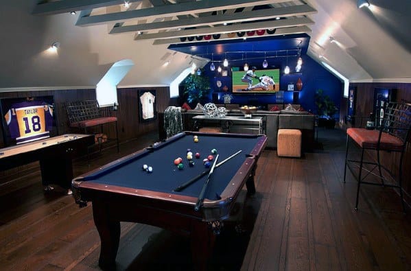 A cozy game room with a pool table, sports jerseys on walls, and a TV showing a baseball game in the background