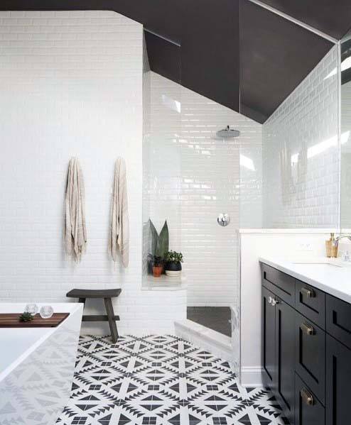 Modern bathroom with patterned black and white tile flooring, glass shower, and black vanity.