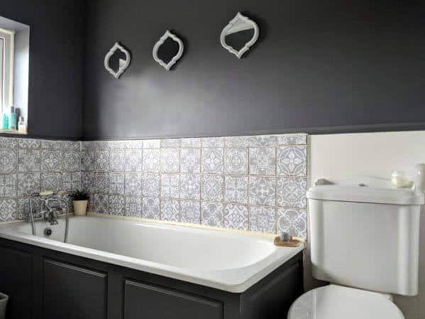 Black and white bathroom with patterned tile backsplash, built-in tub, and decorative mirrors.