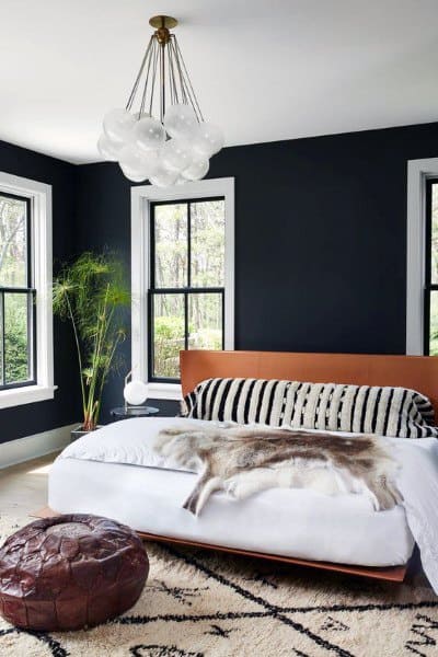 Modern black bedroom with large windows, leather accents, and a cloud-inspired chandelier.