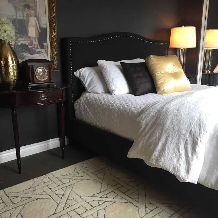 Luxurious bedroom with black bed, white bedding, and gold accent decor.