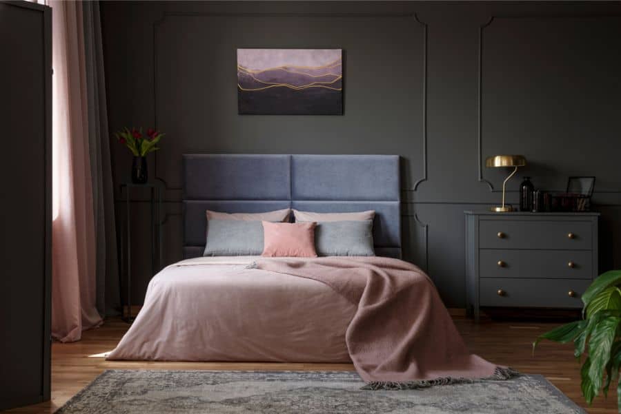 Elegant bedroom with grey accent wall, pink bedding, and modern decor elements.