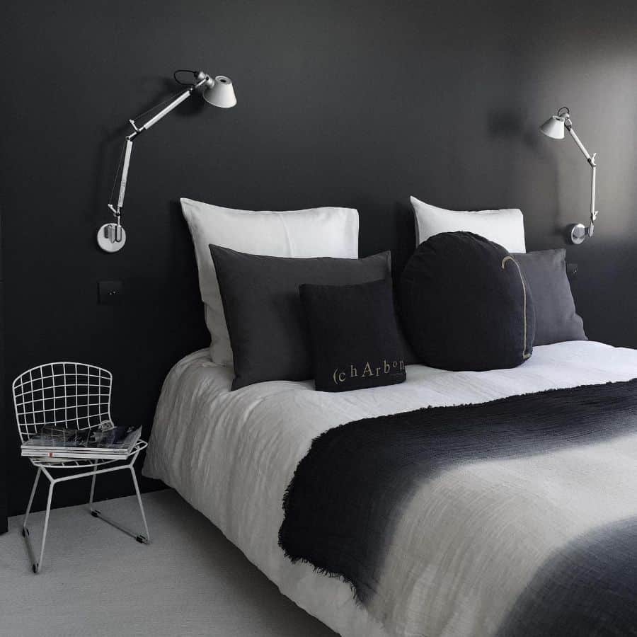 Modern bedroom with black accent wall, monochrome bedding, and industrial wall lamps.