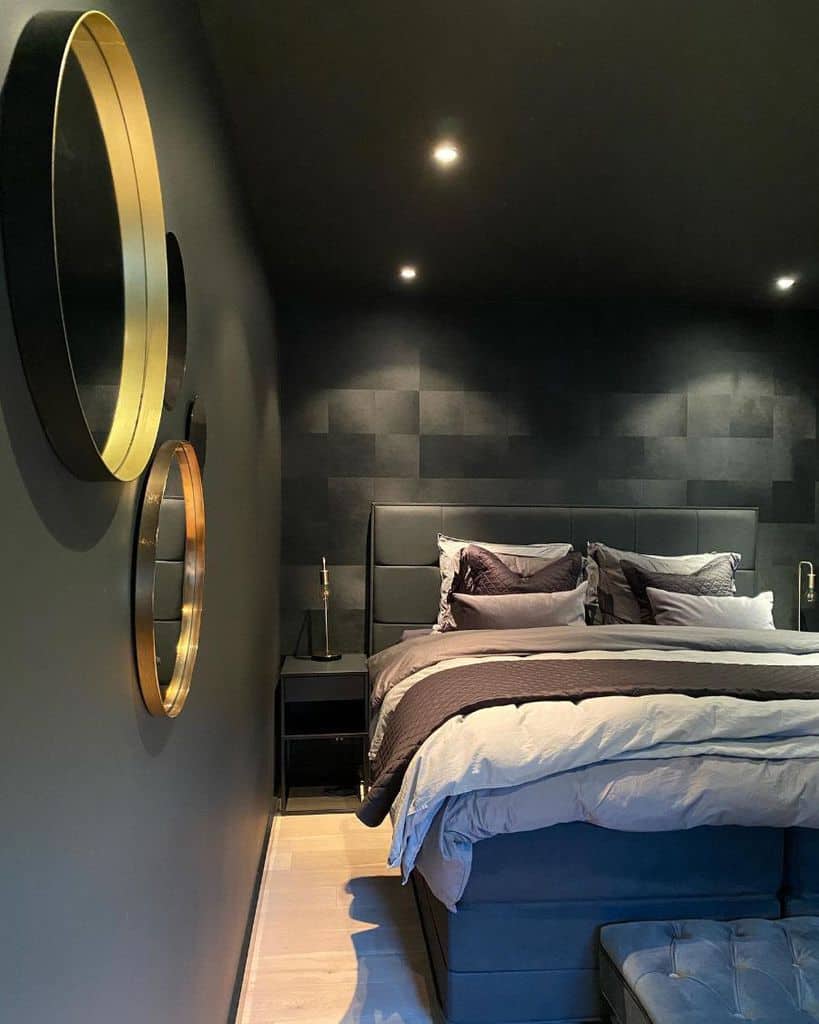 Sleek black bedroom with gold accent wall mirrors and cozy layered bedding.