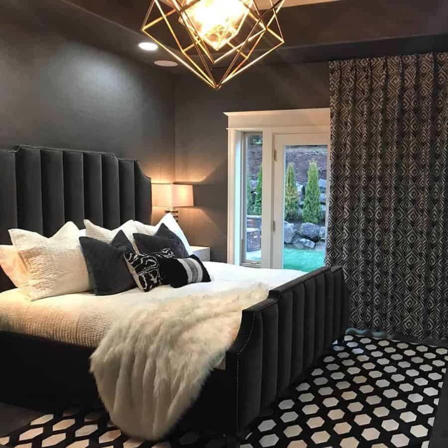 Stylish black bedroom with geometric lighting, patterned rug, and garden view.