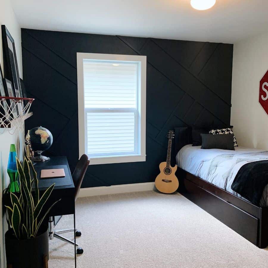 Modern kids' bedroom with black accent wall, desk, guitar, and basketball hoop.