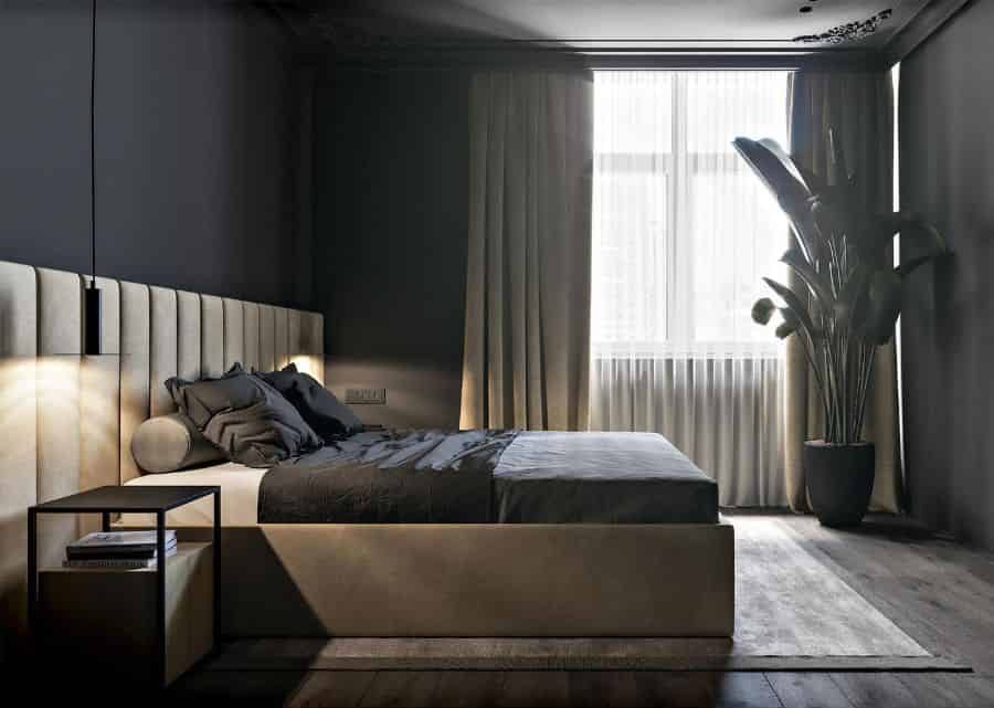 Sleek black bedroom with beige bed, large plant, and hardwood floors.