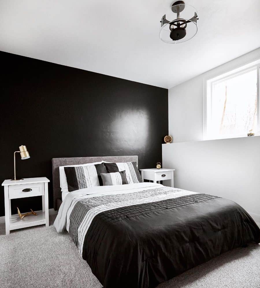 Minimalist bedroom with black accent wall, monochrome bedding, and white nightstands.