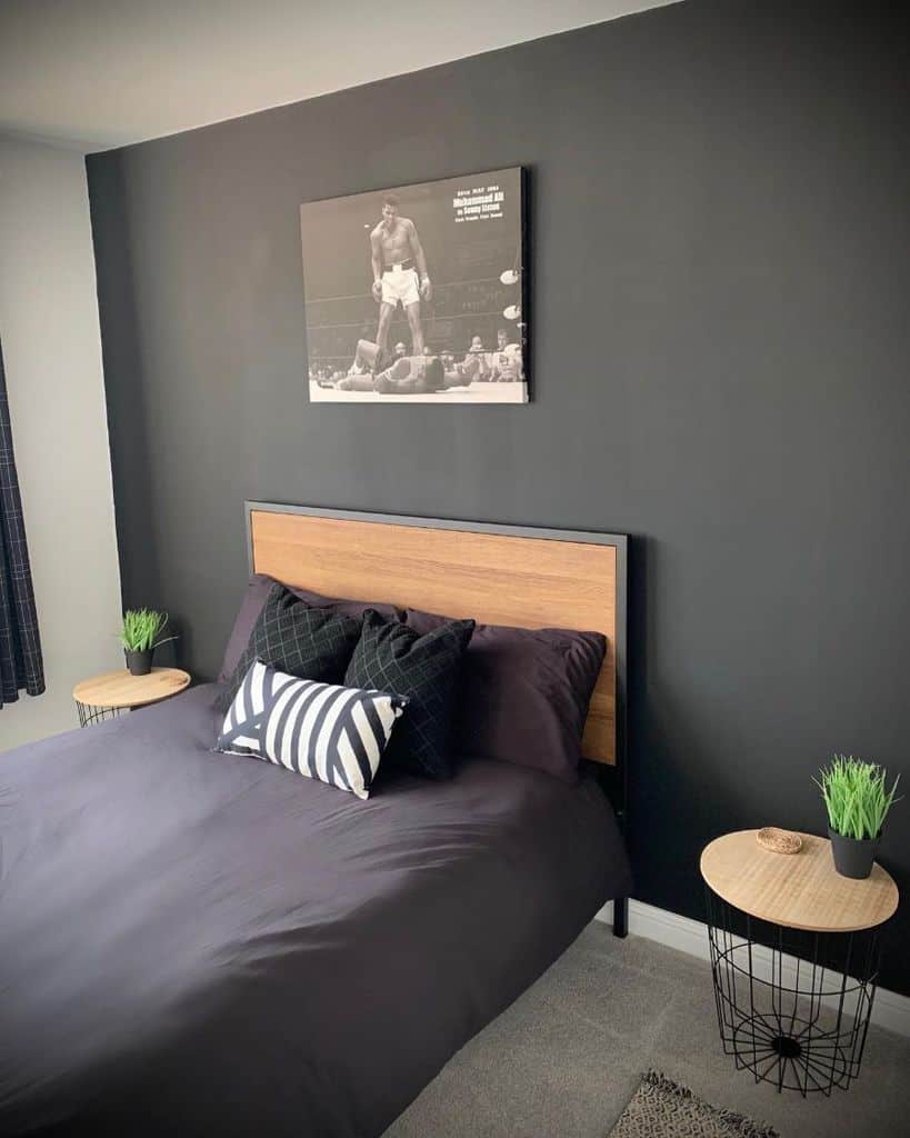 Modern bedroom with black accent wall, wood headboard, and monochrome decor.