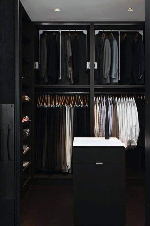 A well-organized wardrobe with jackets, shirts, trousers, and shoes neatly arranged in a modern closet