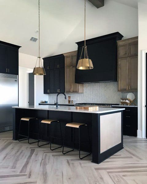 Black and wood kitchen cabinets with gold pendant lights and a large island with seating.