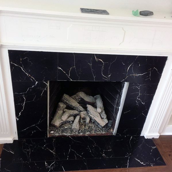 Black marble fireplace with decorative logs and a white mantel.