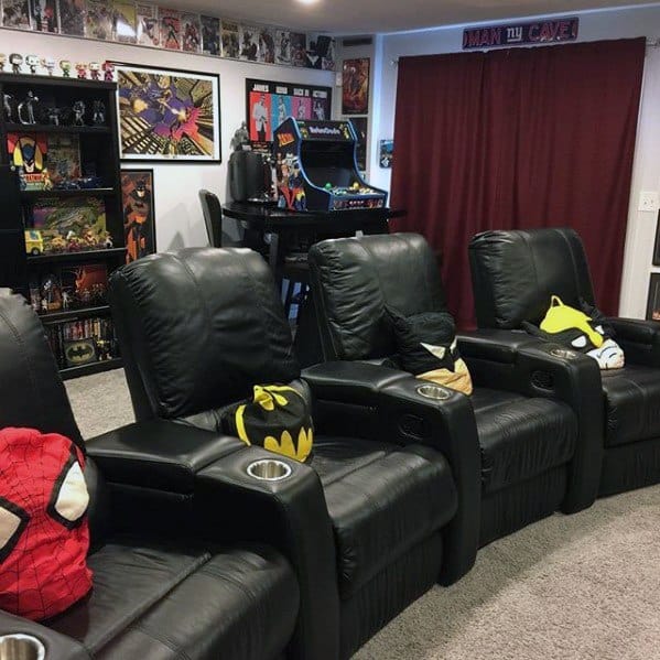 Home theater with black recliners, superhero pillows, comic collectibles, and an arcade machine