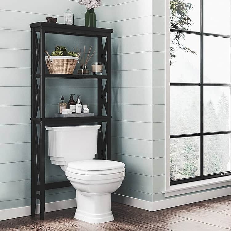 Black over-the-toilet shelving unit with baskets, towels, and bath products in a modern bathroom.