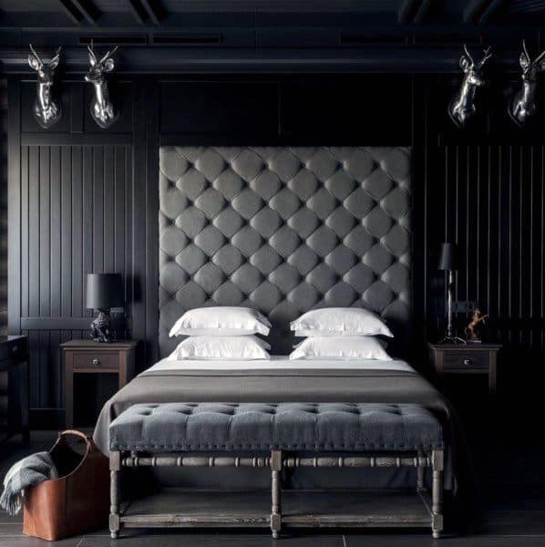 Sophisticated black bedroom with tufted headboard, bench seating, and dark wood furniture.