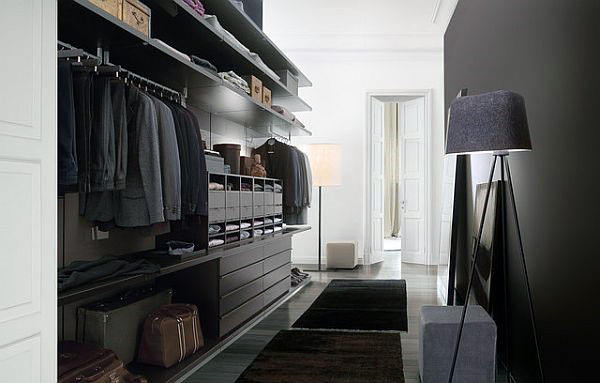 A sleek, modern walk-in closet with neatly arranged clothes, shelves, and dark walls illuminated by standing lamps