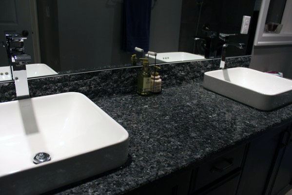 Bathroom with black granite backsplash, double sinks, and large mirror.