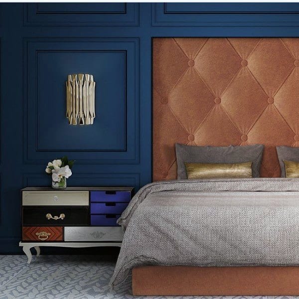 Luxurious bedroom with navy panel walls, tufted orange headboard, and stylish side table.