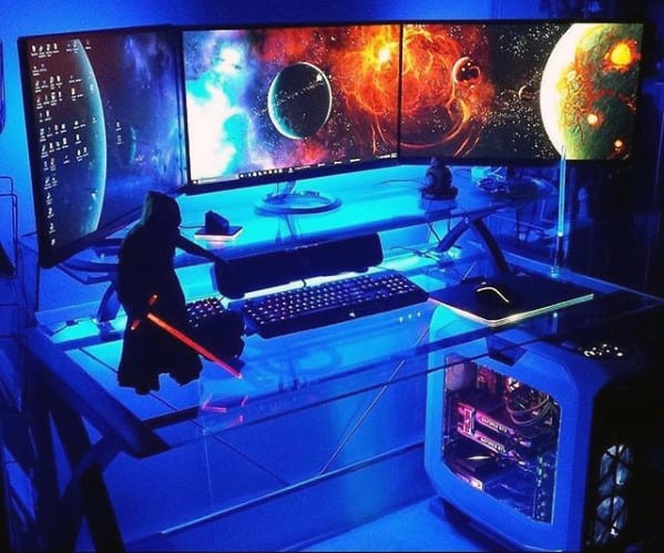 A futuristic gaming setup with three monitors displaying a space theme and glowing LED lights