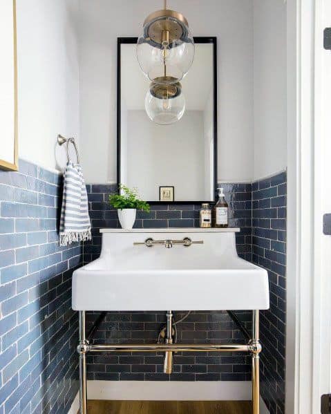 Bathroom with blue beveled subway tile backsplash, pedestal sink, and hanging light fixture.