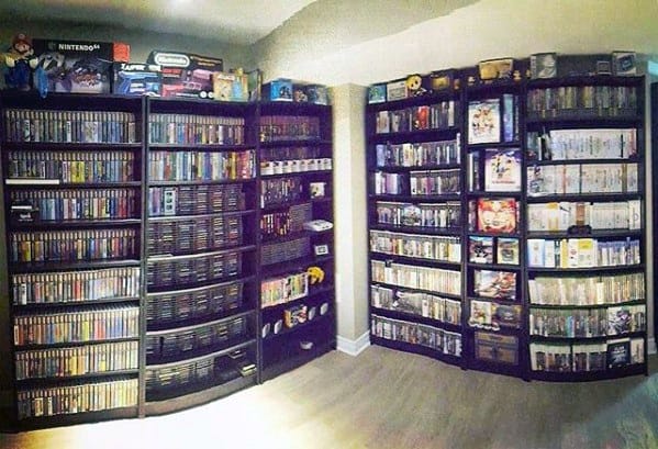 Room with shelves full of video games and consoles, arranged neatly on dark wooden bookcases