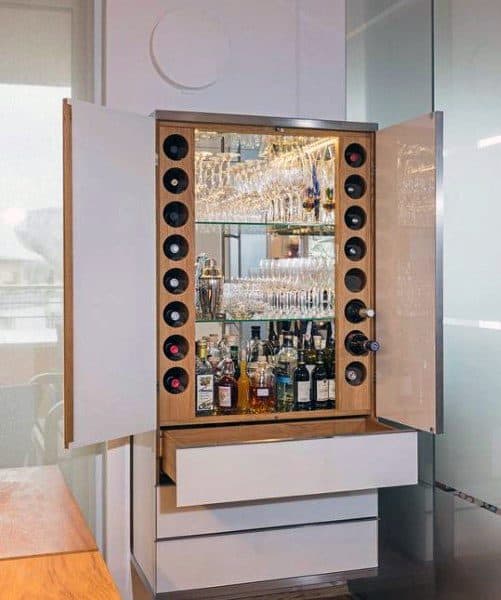 Compact mini bar with built-in wine bottle storage, mirrored back, and glassware display shelves.