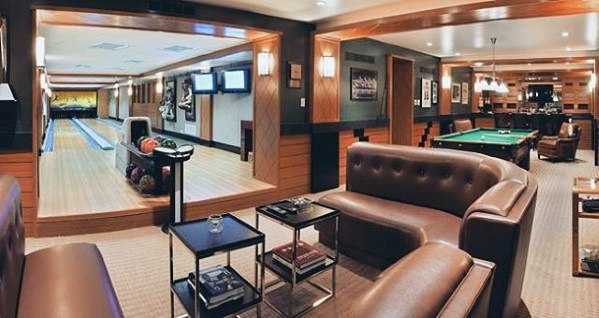 Midcentury modern mancave with leather seating, private bowling alley, pool table, and wood accents.