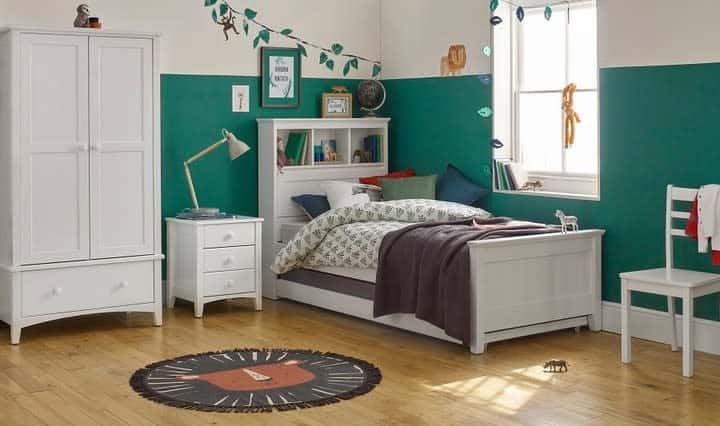 Bright bedroom with green walls, white furniture, a bed, and a window featuring decor such as a rug and animal-themed items