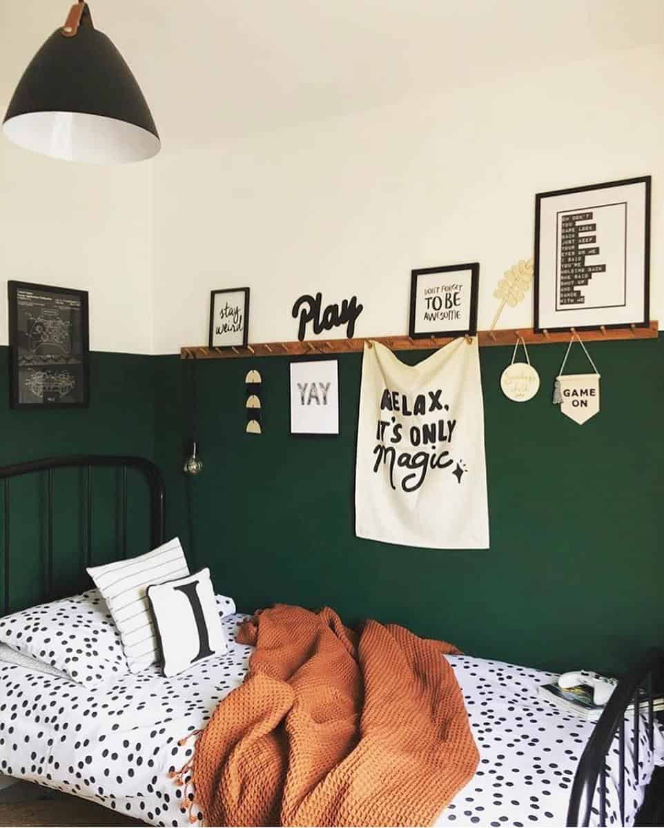 Cozy bedroom with green walls, wall art, a single bed with polka dot bedding, and a warm orange blanket