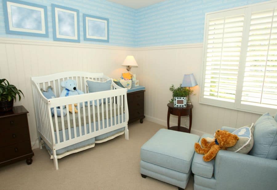 Classic baby boy's room with blue couch, white crib, and soft blue accents.