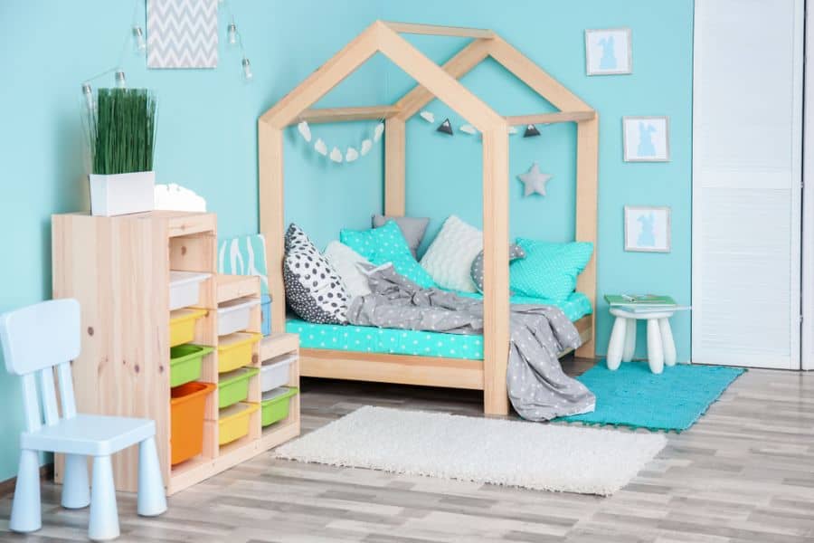 Creative baby boy's room with wooden house bed, colorful storage bins, and playful decor.