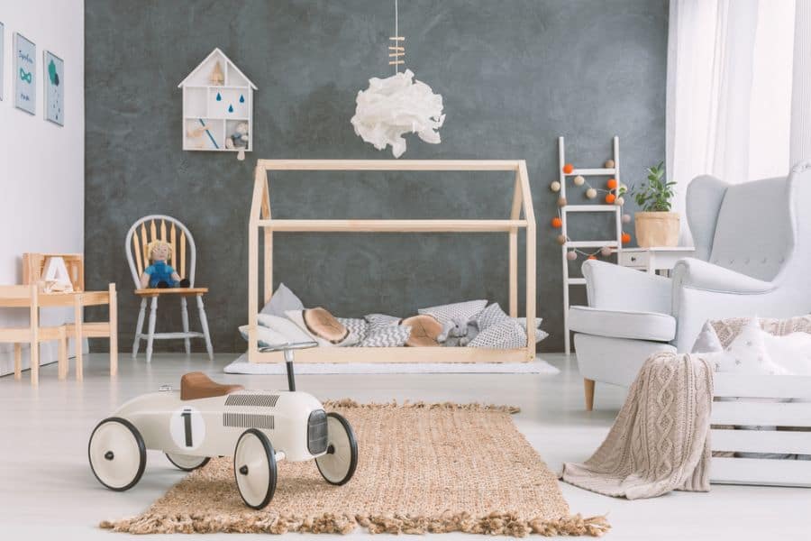 Scandinavian-style baby boy's room with toy car, house bed, and neutral decor elements.