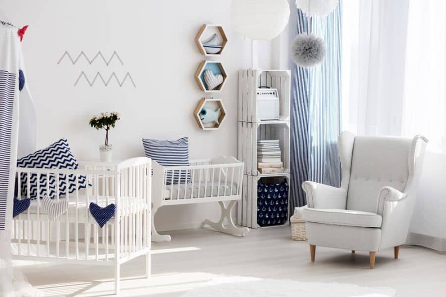 Nautical-themed baby boy's room with white crib, blue accents, and cozy reading chair.