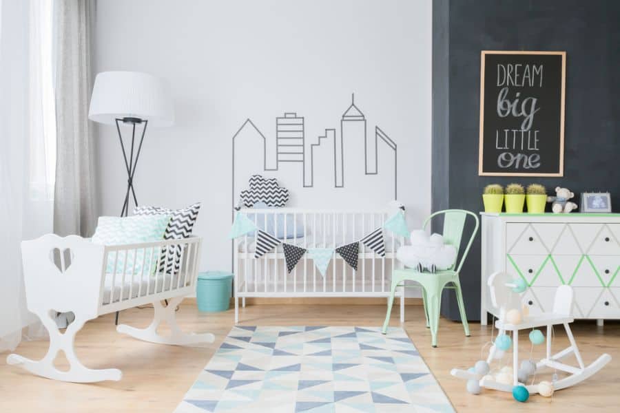 Modern baby boy's room with city skyline wall art, white crib, and geometric decor accents.