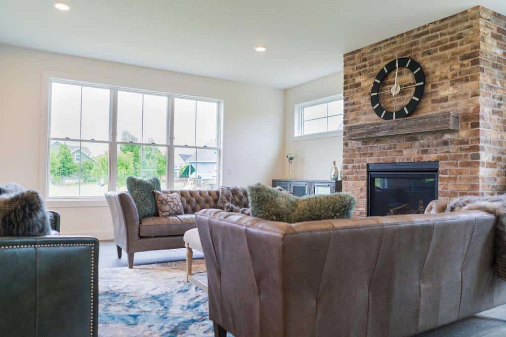 brick fireplace wall with wood mantle and clock classic brown leather sofas 