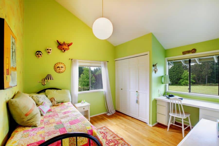 Bright green bedroom with single bed, built-in closet, and desk by window.