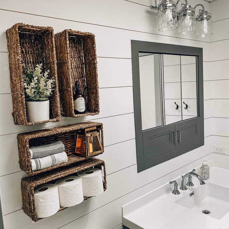 Wall-mounted wicker basket shelves with towels, decor, and toilet paper in a modern bathroom.