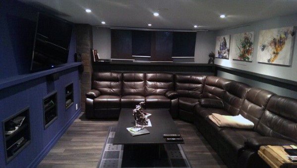 Midcentury modern mancave with large brown leather sectional, navy walls, and minimalist decor.