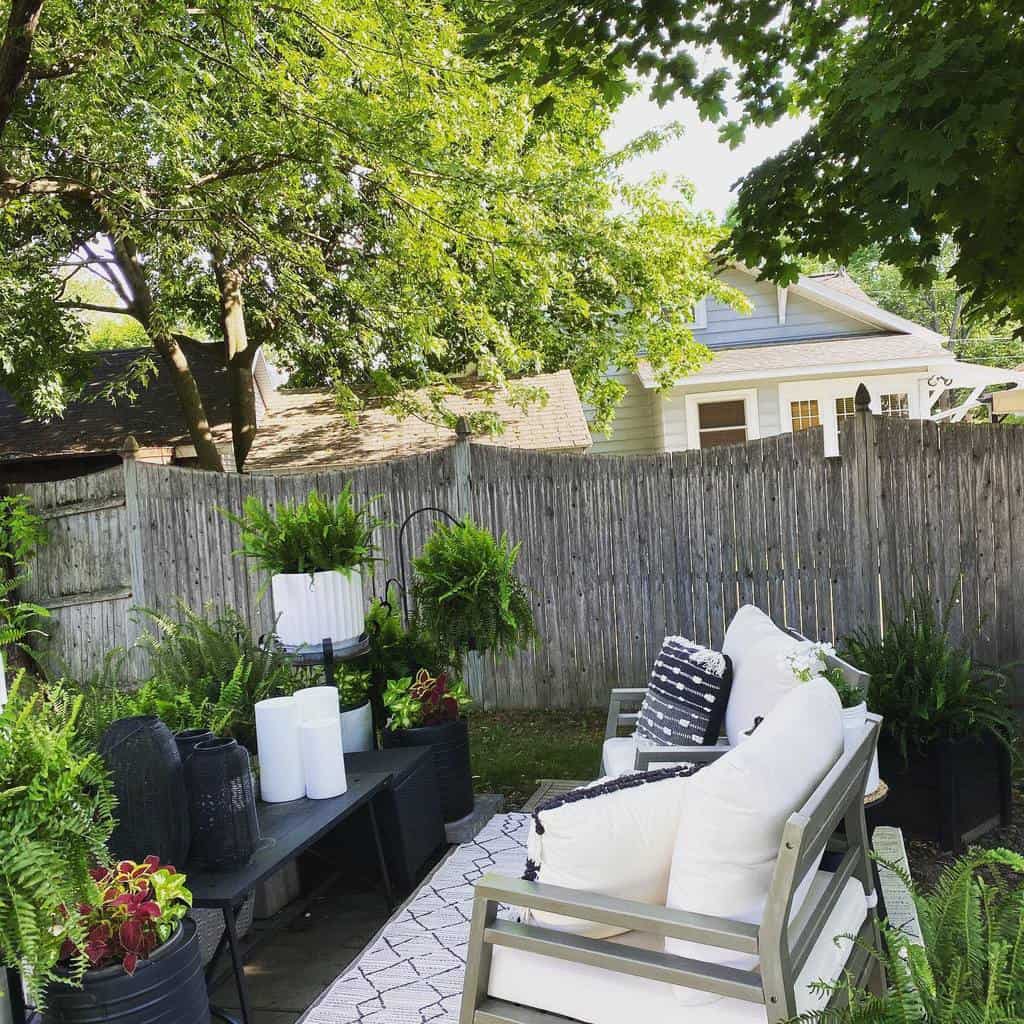 small backyard lots of plants black desk and gray chairs 