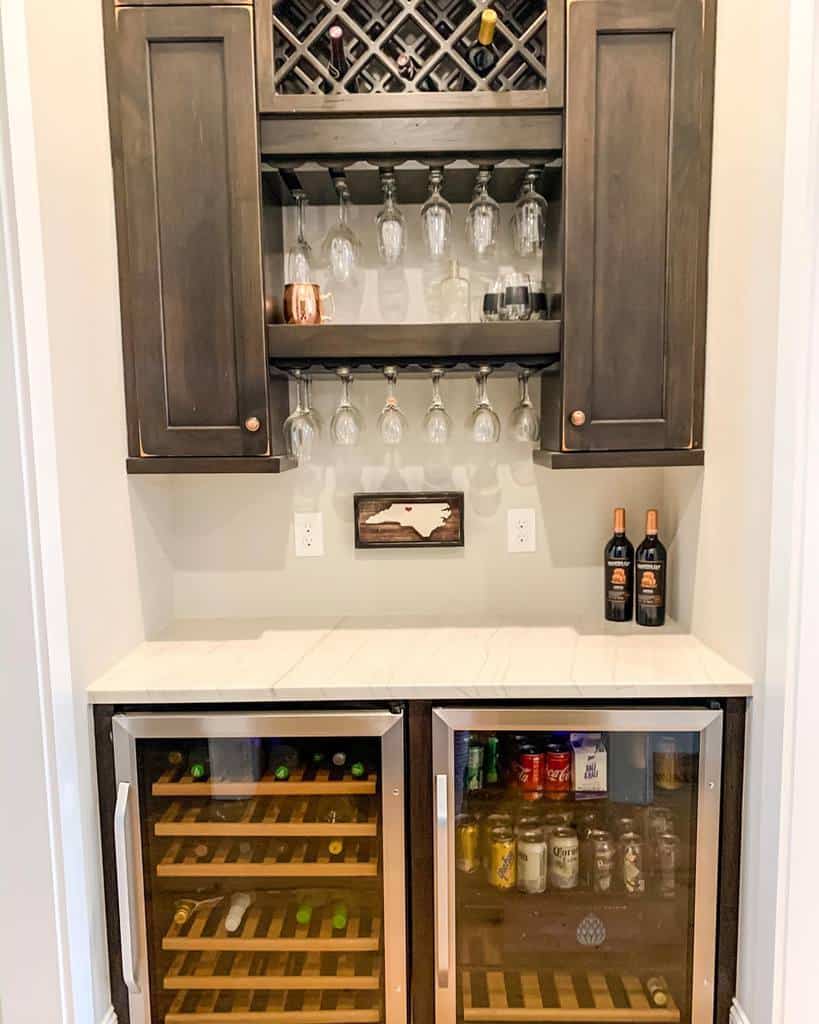 Compact wet bar with wine rack, glass holders, dual beverage coolers, and dark wood cabinets.