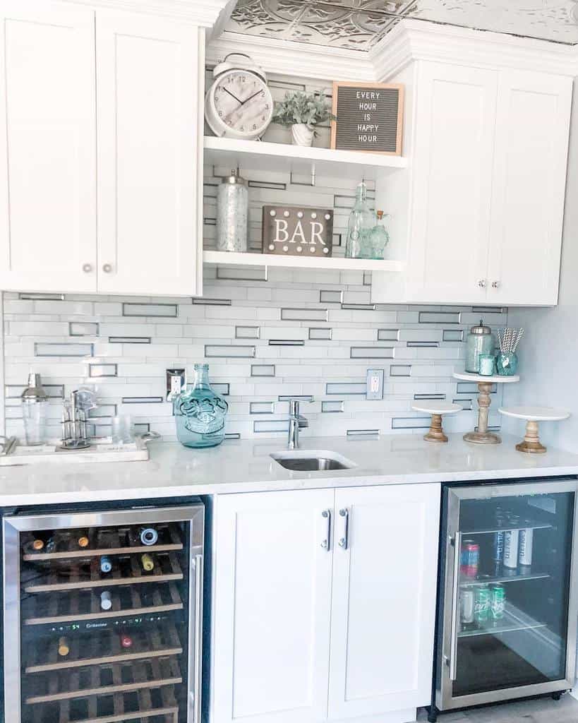 Bright wet bar with white cabinets, mirrored backsplash, wine cooler, and decorative accents.