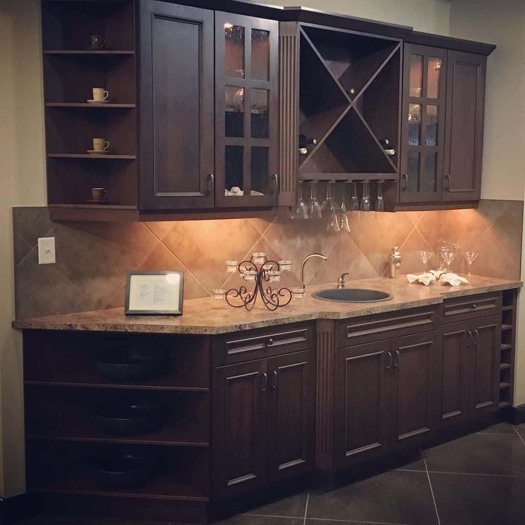 Traditional wet bar with dark wood cabinets, wine storage, tiled backsplash, and curved countertop.