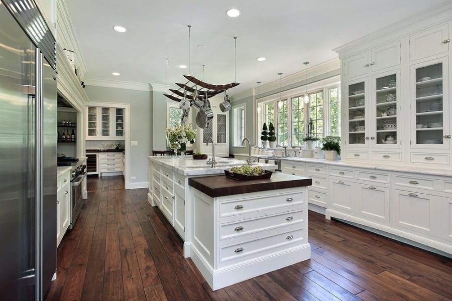 Spacious kitchen with white cabinets, wooden floor, and a central island under stylish pendant lights