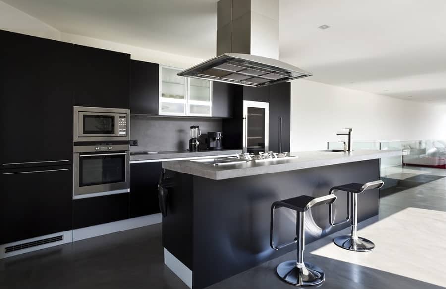 Modern kitchen with black cabinets, stainless appliances, and a gray island featuring two stylish bar stools