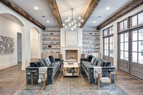 elegant formal living room exposed timber ceiling beans gray couches recessed shelves fireplace 