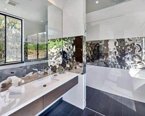 Bathroom with metallic decorative backsplash, floating vanity, and large mirror.