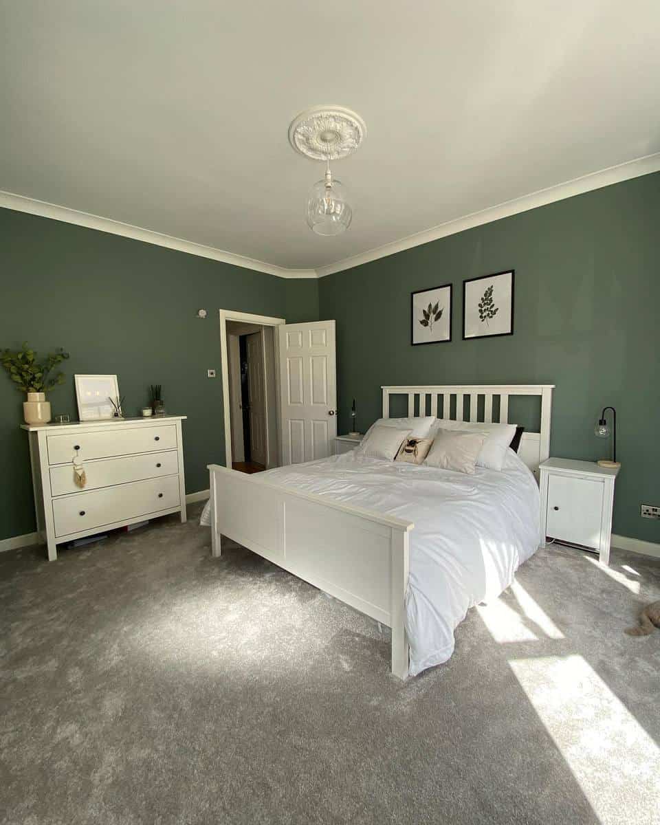 Bedroom with green walls, white furniture, bed, and decor, sunlight streaming in, grey carpet flooring