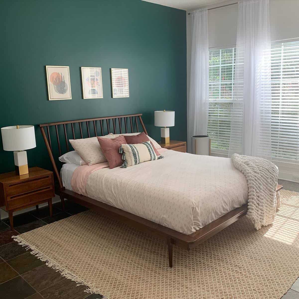 Cozy bedroom with a wooden bed, white bedding, green accent wall, and large windows letting in natural light